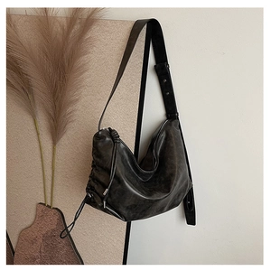 Close-up of vintage black pleated leather shoulder bag with drawstring detail and wide strap