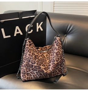 Detail of leopard print tote bag with black leather straps and silver metal chain accessory