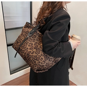 Close-up of a large leopard print tote bag with black leather straps in a lifestyle setting