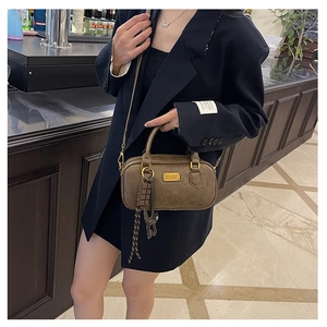 Dettaglio borsa Boston marrone scuro con placca dorata e tracolla intrecciata