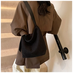 Detail view of black faux fur hobo bag with smooth leather shoulder strap on a model