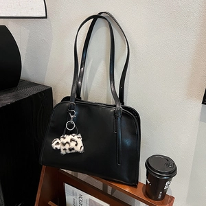 Détail d'un sac hobo noir en similicuir avec un charme en peluche léopard