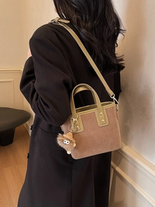 Sac seau vintage en daim marron avec charm en peluche porté à l'épaule sur mannequin