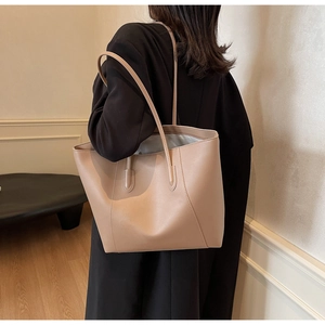 Detail view of khaki tote bag showing supple faux leather texture and slender shoulder straps
