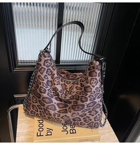Detail showing leopard print texture, leather strap, and metal chain of the hobo bag