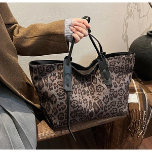 Detail shot of large leopard print tote bag with black faux leather handles and texture