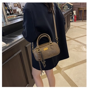 Dettaglio della borsa Boston vintage marrone con hardware dorato e ciondolo cioccolato