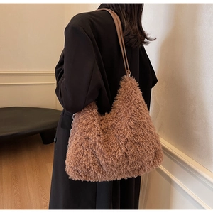 Detail of a brown faux fur shoulder bag with slender leather strap worn by a model