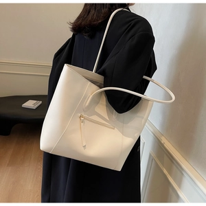 Detailed view of large cream tote bag featuring a front zipper pocket and long leather straps