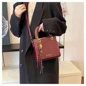 Detail of burgundy leather handbag with gold metal charm and BLONMAY logo print