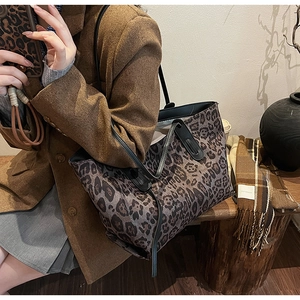 Detail of stylish leopard print tote bag with black handles in cozy indoor setting