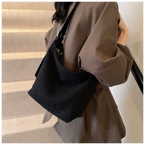 Detail of black textured wool bucket bag with adjustable leather shoulder strap