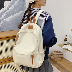 Detailed side view of a large white canvas backpack shown in a cozy indoor setting