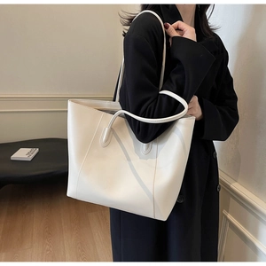 Close-up of white leather tote bag with long shoulder straps and spacious interior