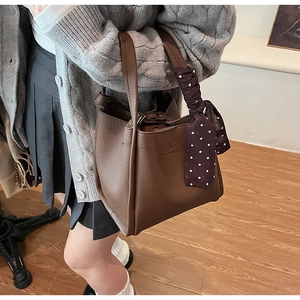 Detail of brown litchi leather bucket bag featuring a decorative polka dot scarf wrap