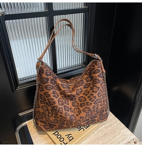 Detailed close-up of leopard print tote bag featuring a silver chain and leather strap