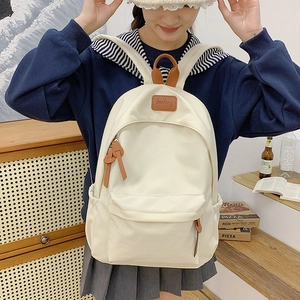 Detail view of cream canvas backpack with leather accents and kunkang label in room