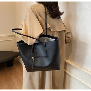 Close-up of black leather tote bag with long zipper pocket and matte texture detail
