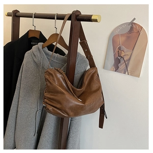 Detailed view of a brown vintage pleated hobo bag hanging on a minimalist clothes rack