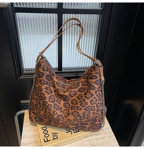 Macro detail of large leopard print tote bag with leather straps and silver chains