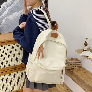 Detail of off-white minimalist canvas backpack featuring leather logo and multi-pocket design