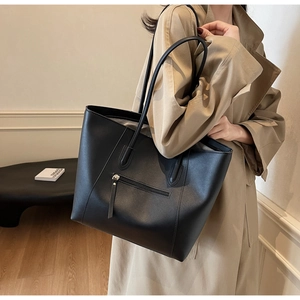 Detail view of large black tote bag featuring a practical zipper pocket and long shoulder straps