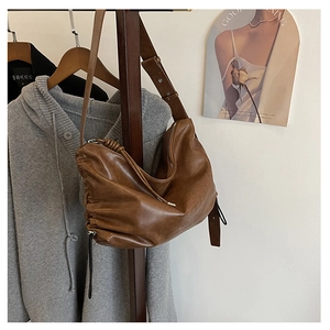 Detail of dark brown leather hobo bag with side pleats and textured finish