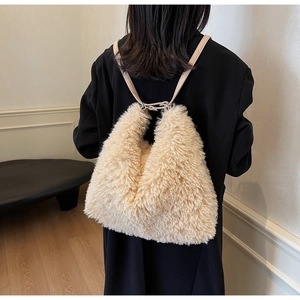 Close-up of fluffy cream faux fur backpack with thin leather straps on a black blazer