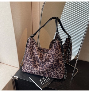 Close-up of leopard print tote bag featuring black leather strap and silver chain detail