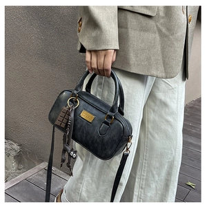Detail of vintage black leather Boston bag with gold metal logo and cute cat charms