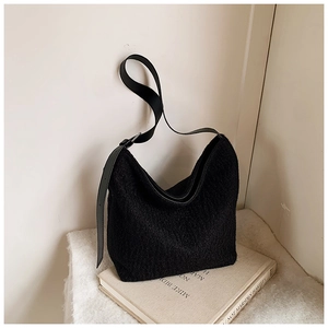 Fashionable black faux shearling shoulder bag with leather strap on a minimalist setup