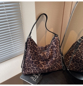 Detail of leopard print hobo bag with sleek black leather strap and silver chain accent