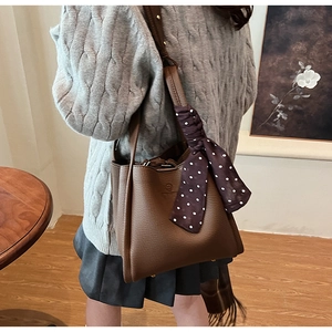 Detail of dark brown lychee grain leather bucket bag with decorative polka dot silk scarf