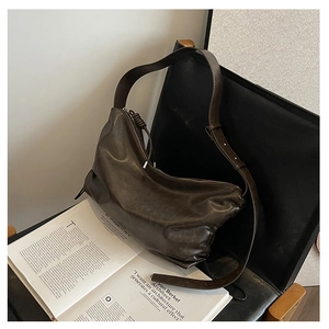 Detail of vintage brown leather hobo bag with adjustable strap on a chair