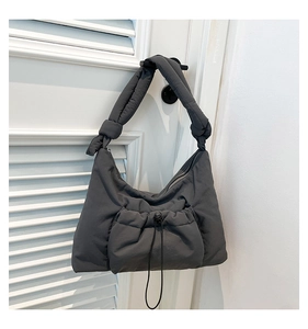 Detail of dark grey quilted nylon bag with functional drawstring pocket and knotted strap