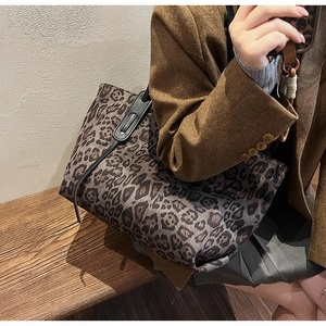 Detailed view of leopard print tote bag with reinforced black straps on model