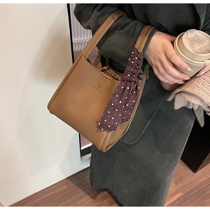 Detailed view of brown lychee leather bucket bag with elegant polka dot silk scarf detail