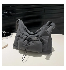 Detail view of dark grey padded nylon shoulder bag with drawstring pocket and knotted strap