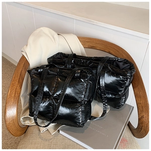 Comparison of large and small glossy black quilted puffer tote bags on a wooden chair