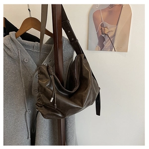 Detail of dark coffee leather hobo bag with drawstring knot and smooth metal zipper