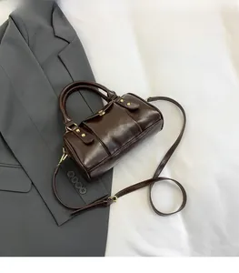 Detailed view of deep brown Boston bag with golden studs and adjustable strap