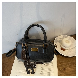 Detail of black retro Boston bag with gold metal plate and cute charms on books