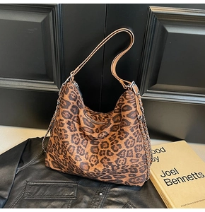 Detailed close-up of leopard print tote bag texture with metal chain and zipper closure