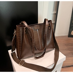 Close-up of dark brown crocodile embossed leather tote bag with wide canvas strap