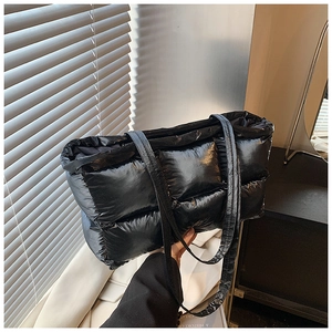 Close-up of black quilted puffer tote bag with glossy nylon texture and padded design