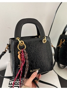 Chic black crossbody bag with pleated finish, golden logo and woven charm detail