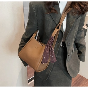 Close-up of brown litchi leather bucket bag with a stylish polka dot silk scarf handle