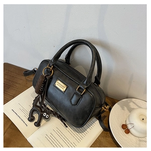 Detail of black Boston bag with gold plate, cute bag charm and adjustable strap