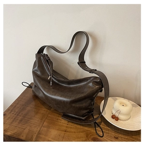Detailed view of deep brown leather hobo bag with adjustable strap on a wooden table