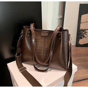 Close-up of dark brown crocodile pattern tote with wide woven detachable strap